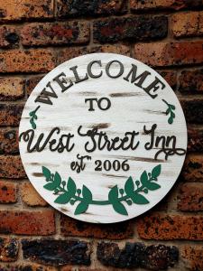 a sign on a brick wall that reads welcome to west street inn at West Street Inn - Ermelo in Ermelo