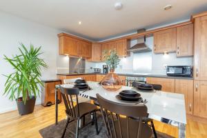 una cocina con armarios de madera, mesa y sillas en Riverview Apartments en Glasgow