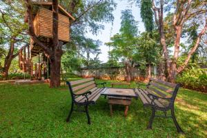 two benches and a picnic table in a park at Morning Dew Retreat by StayVista - Modern interiors, Indoor games, Lush greenery, Pool & Gazebo await your escape in Nashik
