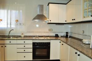 リョレート・デ・マルにあるVilla Dorisの白いキャビネットとコンロ付きオーブンを備えたキッチン