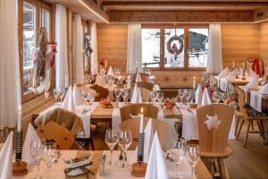 un comedor con mesas y sillas y copas de vino en Hotel Edelweiss, en Blatten im Lötschental