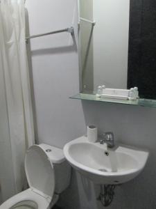 a bathroom with a toilet and a sink and a mirror at LeGreen Suite Setiabudi in Jakarta