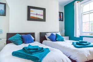 two beds with blue towels on top of them in a room at Seagulls Nest Beachfront Apartment With 3 Bedrooms in Hastings