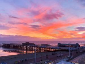 a view of a pier with a sunset at Seagulls Nest Beachfront Apartment With 3 Bedrooms in Hastings