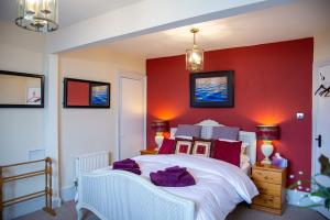 um quarto com uma cama branca e uma parede vermelha em Seagulls Nest Beachfront Apartment With 3 Bedrooms em Hastings