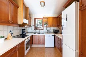 a kitchen with wooden cabinets and a white refrigerator at Sitges Casa del Mar Impresionantes vistas al mar in Sitges