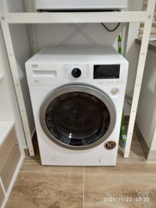 a white washing machine with a tv on a shelf at Poema Apartment in Casalecchio di Reno