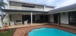 a villa with a swimming pool and a house at NoniSands Guesthouse in Uvongo Beach