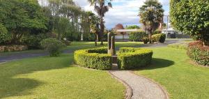 a park with bushes and a sign in the grass at Maple Lodge Motel in Matamata