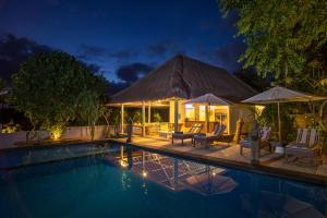 a villa with a swimming pool at night at Komodo Garden in Nusa Lembongan