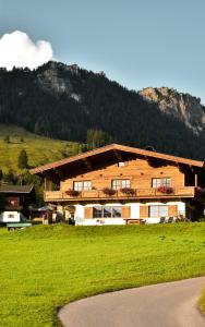 ein großes Holzgebäude mit einem Berg im Hintergrund in der Unterkunft Ferienwohnung Buchau in Fieberbrunn
