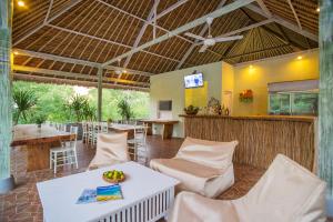 a restaurant with white tables and chairs and a bar at Komodo Garden in Nusa Lembongan
