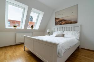 a bedroom with a large white bed with two windows at Business & Family Ambiente Apartments in Bratislava