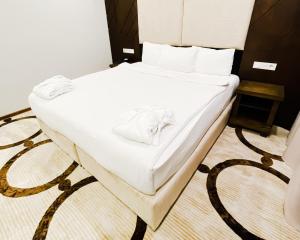 un letto con lenzuola bianche e asciugamani di East Palace Hotel a Almaty