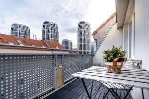 einen Balkon mit einer Holzbank und einer Topfpflanze in der Unterkunft Business & Family Ambiente Apartments in Bratislava