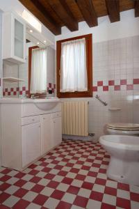 a bathroom with a toilet and a checkered floor at CA RAFFAELLO lovely house near Venice in Noale