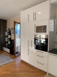 a kitchen with white cabinets and a microwave at Lastochka.mne apartments in Baošići