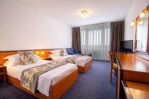 a hotel room with two beds and a desk at Hotel Novi Zagreb in Zagreb