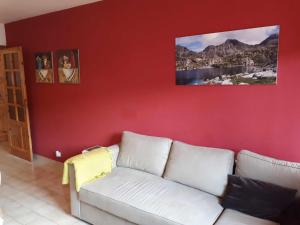 uma sala de estar com um sofá branco contra uma parede vermelha em Apartamento Vall Fosca em Senterada