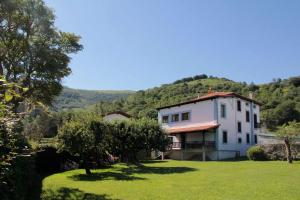 a large white house with a hill in the background at Villa con Jardín para 12 personas in Beinza-Labayen