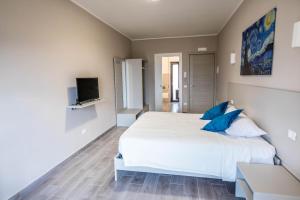 1 dormitorio con 1 cama blanca grande con almohadas azules en Il Gelso Guest House, en Catanzaro