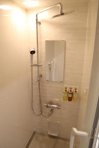 a bathroom with a shower with a toilet and a mirror at C＆Jホテル in Tokyo