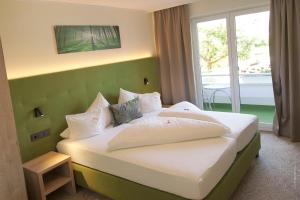 a bedroom with a bed with a green headboard at Hotel Pachernighof in Velden am Wörthersee