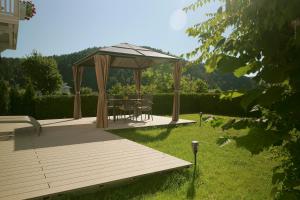 a wooden deck with a gazebo in a yard at Hotel Pachernighof in Velden am Wörthersee