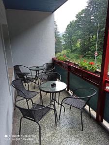 eine Reihe von Tischen und Stühlen auf einem Balkon mit einem Fenster in der Unterkunft Penzion Modřanka in Pec pod Sněžkou