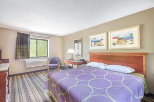 a hotel room with a bed and a desk and a window at Super 8 by Wyndham Tilton/Lake Winnipesaukee in Tilton