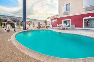 a large swimming pool in front of a house at Super 8 by Wyndham San Antonio/I-35 North in San Antonio