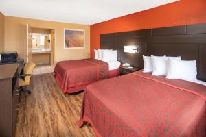 a hotel room with two beds and orange walls at Days Inn by Wyndham Tupelo in Tupelo