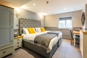 a bedroom with a bed with yellow pillows and a desk at Kinloch Hotel, Isle of Arran in Blackwaterfoot
