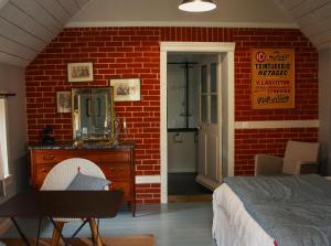 1 dormitorio con pared de ladrillo rojo, cama y espejo en Les gites de Kerégal - la cabane de Charlotte, en Plouha