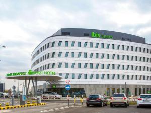 un gran edificio blanco con coches estacionados frente a él en ibis Styles Budapest Airport en Vecsés