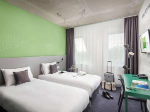 a hotel room with two beds and a green wall at ibis Styles Budapest Airport in Vecsés