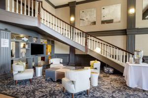 a living room with a staircase and white furniture at Clarion Hotel Seekonk - Providence in Seekonk