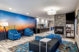 a living room with blue chairs and a fireplace at Comfort Inn & Suites in Emporia