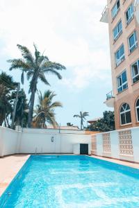 a swimming pool in front of a building with palm trees at Lux Suites APA Apartments Nyali in Mombasa
