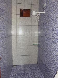 a bathroom with a shower with blue and white tiles at CHALÉ COQUEIROS in Icapuí