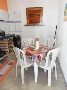 a table with white chairs and a table with a quilt on it at CHALÉ COQUEIROS in Icapuí