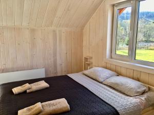 a bed in a wooden room with a window at Shum Cheremosha in Verkhovyna +109 photos