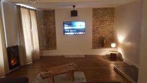 a living room with a fireplace and a tv on the wall at Appartement spacieux et atypique in Sedan