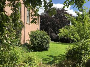 a building with a yard with green grass and trees at Swinton Manse & Gardens in Swinton