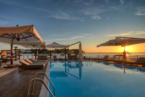 a swimming pool with chairs and umbrellas on a building at BO Hotel Palazzo in Poreč