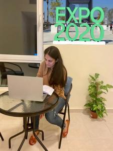a woman sitting at a table with a laptop at Expo Backpackers in Dubai