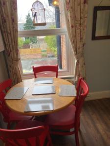 une table et des chaises en bois devant une fenêtre dans l'établissement Grace Stays, à Ellesmere Port