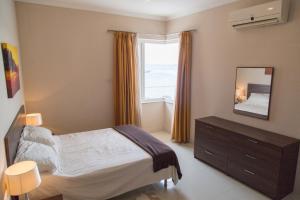 a bedroom with a bed and a mirror and a window at Riviera Holiday Apartments - Seafront - Wifi in Marsaskala