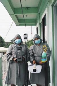 two people in protective gear standing in front of a building at Dragonfly Apartments and Transient House in Bacoor