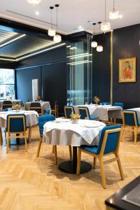 a restaurant with white tables and blue chairs at Habitat Hotel Tirana in Tirana
